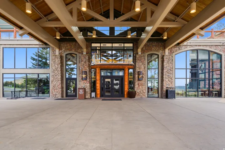 Stone facade with expansive windows, a prominent covered entry, and exposed wood ceiling beams