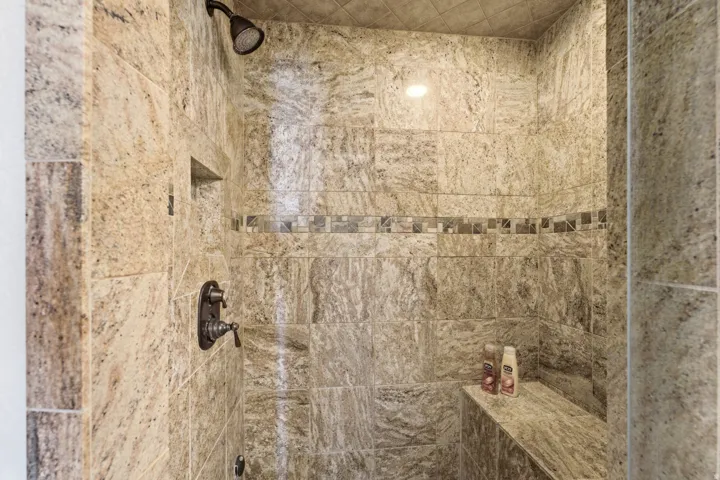 Tile shower with a built-in bench, recessed niche, and decorative tile accent band