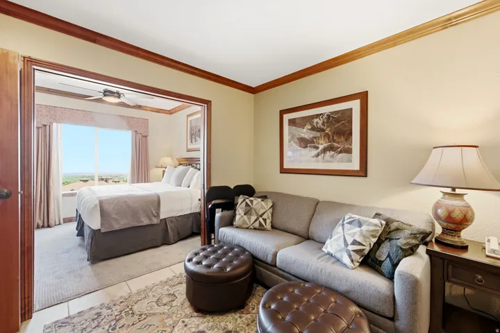 Open concept living area with crown molding, a bedroom with a ceiling fan, and large windows