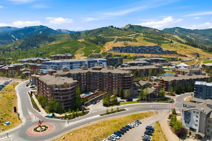 Mountainous backdrop surrounding a community of multi-story buildings, featuring several structures with multiple balconies and a central roundabout