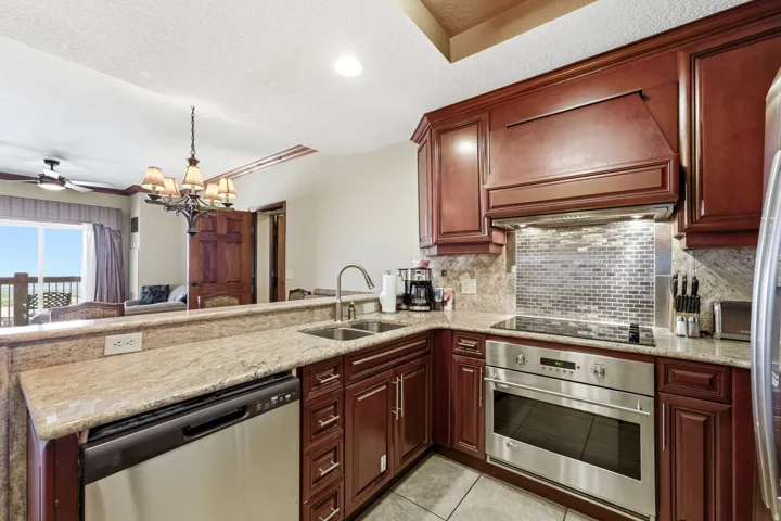 Gourmet kitchen featuring rich wood cabinetry, stainless steel appliances, granite countertops, and a mosaic tile backsplash