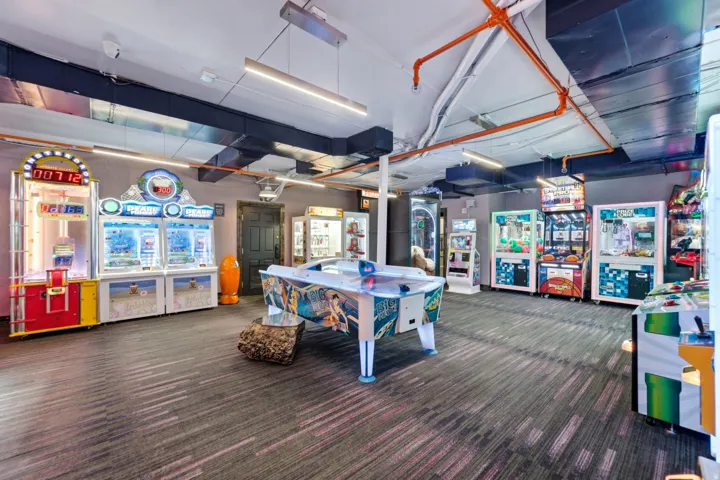 Exposed industrial-style ceiling with overhead lighting and a patterned carpeted floor