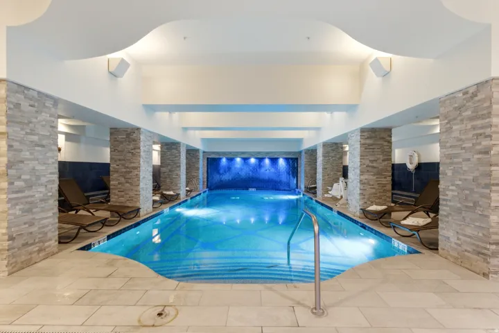 Indoor swimming pool with tiled floor and stone-clad columns