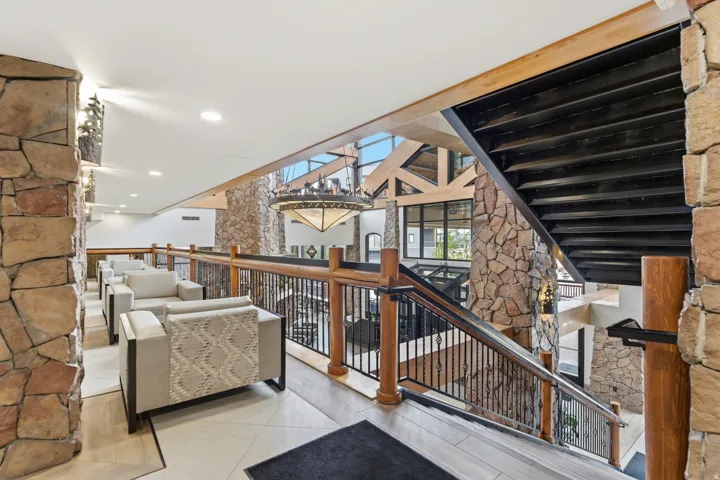 Multi-level interior featuring stone walls, an open staircase with a metal and wood railing, and a vaulted ceiling with exposed beams