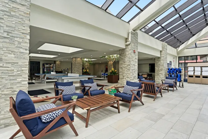 Expansive communal area with a vaulted glass ceiling, stone-clad pillars, and large format tile flooring