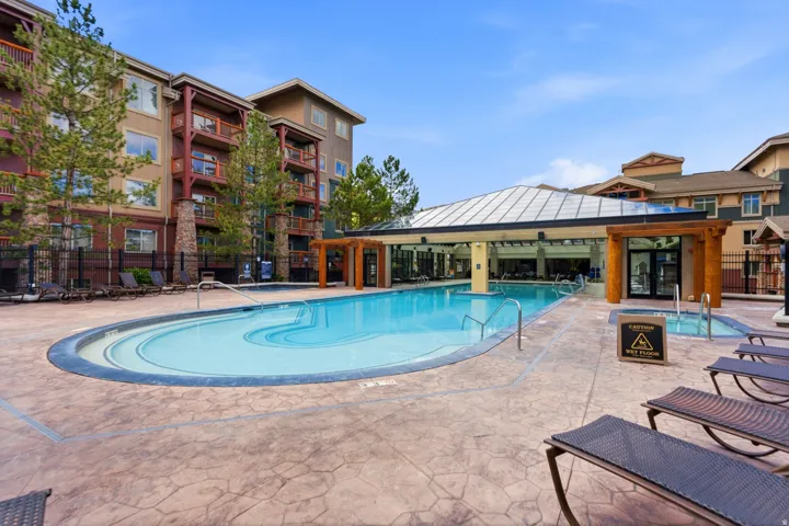 Expansive outdoor pool with an integrated hot tub, surrounded by stamped concrete decking