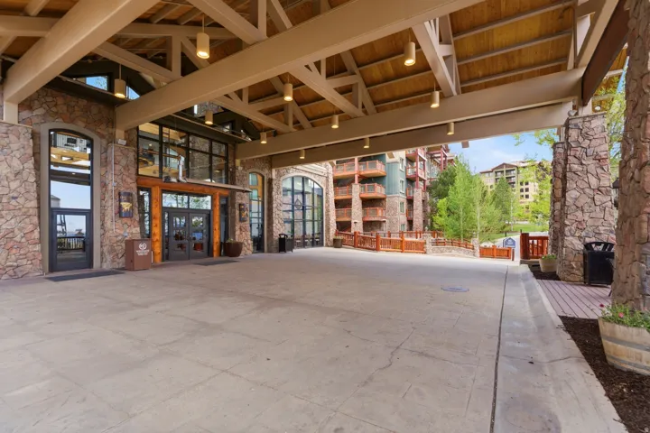 Stone facade with expansive glass doors, exposed wood beam ceiling, and a large porte-cochère