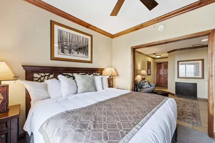 Wood-finish crown molding, wood-finish ceiling fan, wood-finish headboard with branch detailing, and wood-finish door frames