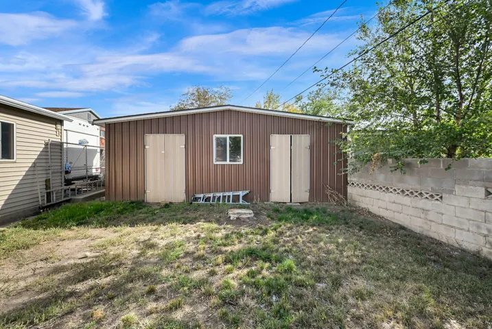 Brown corrugated metal siding structure with a single window and two access doors
