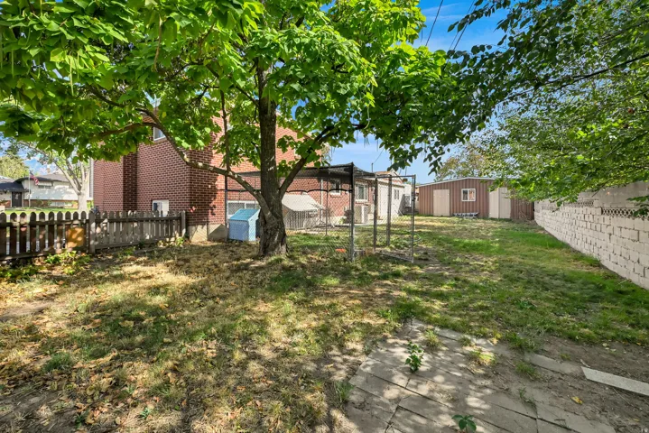 Expansive backyard featuring a mature tree, brick exterior, wood fence, and concrete block wall