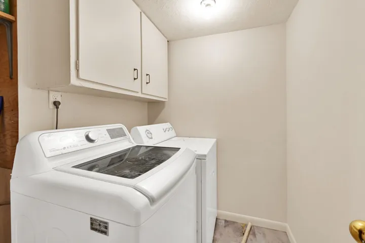 Laundry area featuring overhead cabinetry, recessed ceiling light, and wood-finish flooring