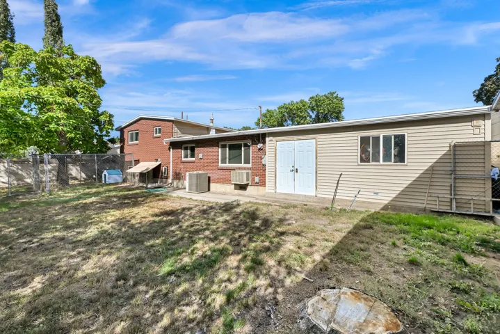 Rear exterior featuring brick and horizontal siding, with a detached shed offering double entry doors and a window