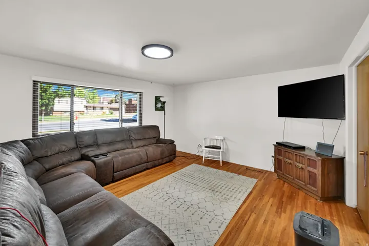 Hardwood flooring, recessed lighting, and a large picture window with horizontal blinds