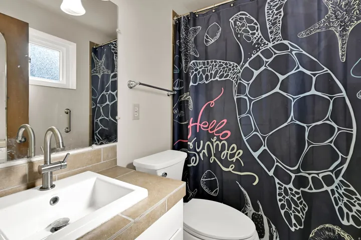 Bathroom featuring a single vanity with a white rectangular sink, a brushed chrome faucet, and a tiled countertop