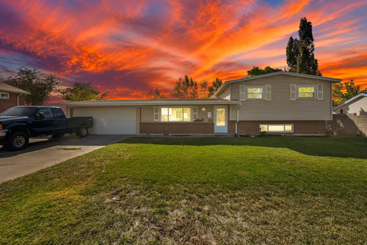 Split-level exterior featuring siding and brick accents, an attached garage, and a concrete driveway