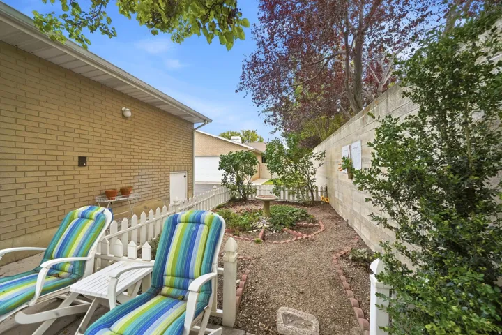 Landscaped outdoor area with gravel path, brick-edged planting beds, and white picket fencing