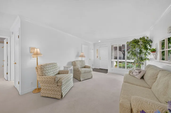 Wall-to-wall carpeting and white walls with crown molding, featuring a front entry door with sidelights and transoms