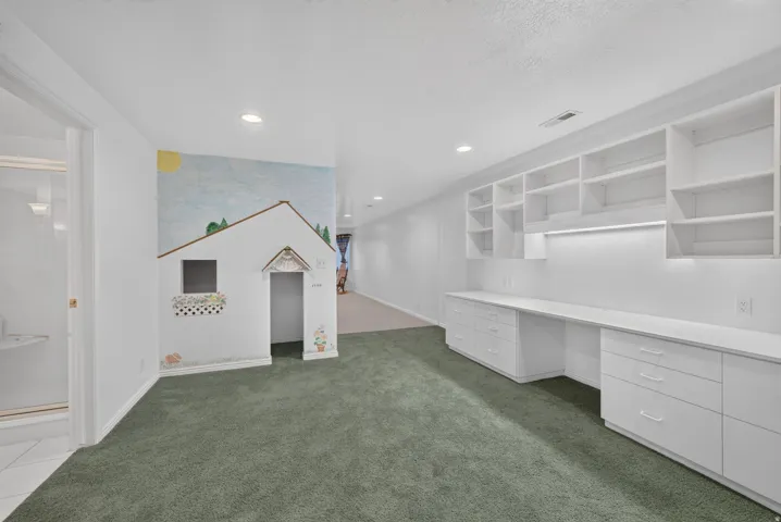 Expansive room featuring built-in white shelving, integrated desk space, and recessed lighting