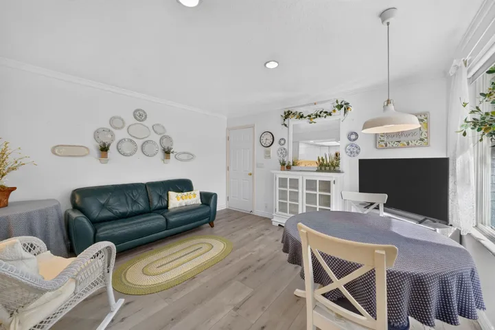 Recessed lighting, wood-finish flooring, crown molding, white painted trim, and a built-in display cabinet