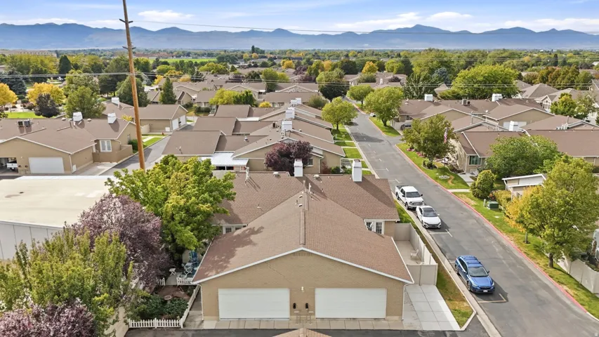 Residential neighborhood with mature trees, mountain backdrop, and paved street
