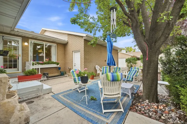Patio area featuring a mature tree, stone landscaping, and a brick exterior
