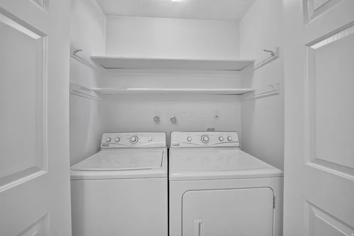 Laundry area with built-in shelving, white washer, and white dryer