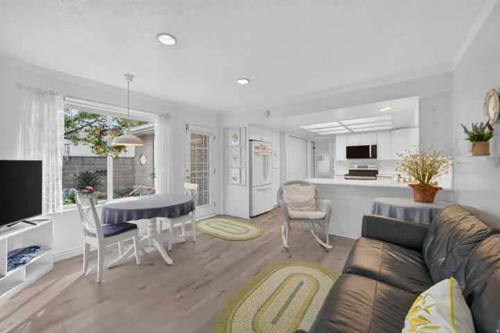 Recessed lighting, wood-finish flooring, white cabinetry, integrated kitchen appliances, and a glass-paneled door