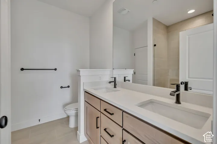 Dual vanity with integrated sinks and black matte faucets, wood-finish cabinetry, light-toned floor tile, and a large mirror