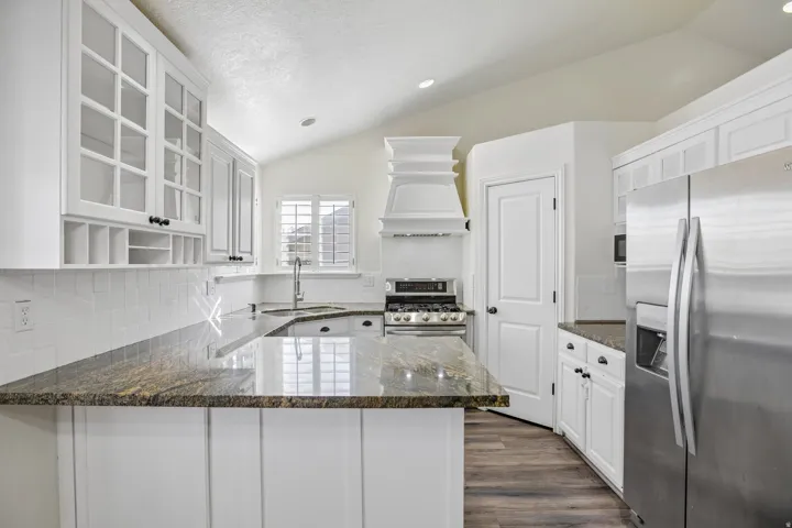 Kitchen featuring white cabinetry, stone countertops, stainless steel appliances, wood-finish flooring, and recessed lighting
