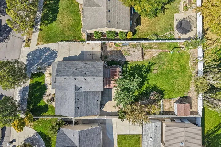 Expansive property featuring a large grass lawn, mature trees, concrete driveway, and a detached shed