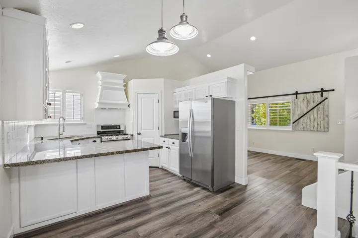 Kitchen featuring white cabinetry, wood-finish flooring, granite countertops, and stainless steel appliances