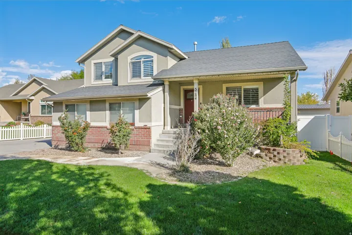 Two-story stucco exterior with brick accents, covered front porch, and a dark asphalt shingle roof