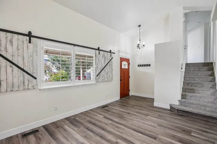 Wood-finish flooring, white walls, and a staircase with carpeted treads