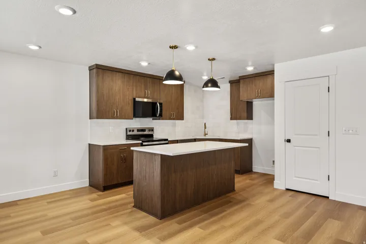 Kitchen featuring wood-finish cabinetry, stainless steel appliances, a center island with a white countertop, and recessed lighting