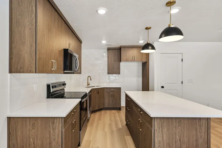 Kitchen featuring wood-finish cabinetry, white solid surface countertops, white subway tile backsplash, and pendant lighting
