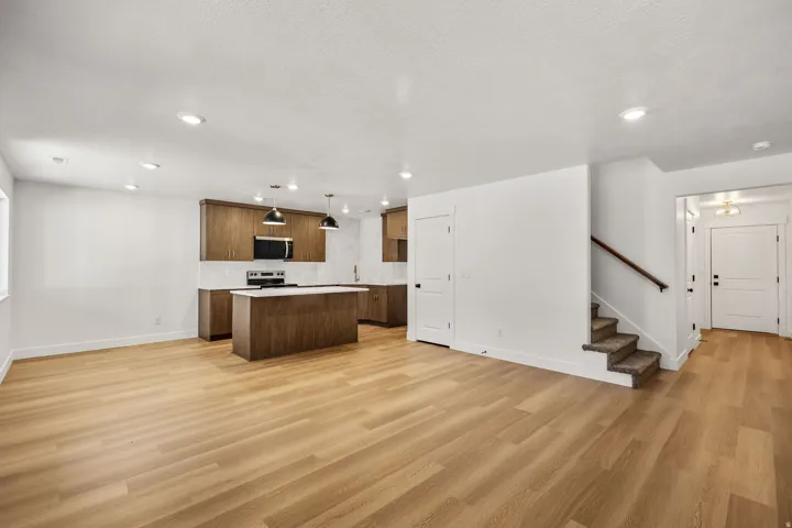 Wood-finish flooring throughout, recessed lighting, wood cabinetry, white countertops, and stainless steel appliances