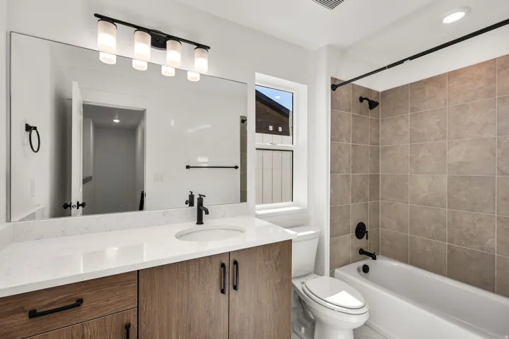 Bathroom with a wood-finish vanity, white countertop, and a large mirror