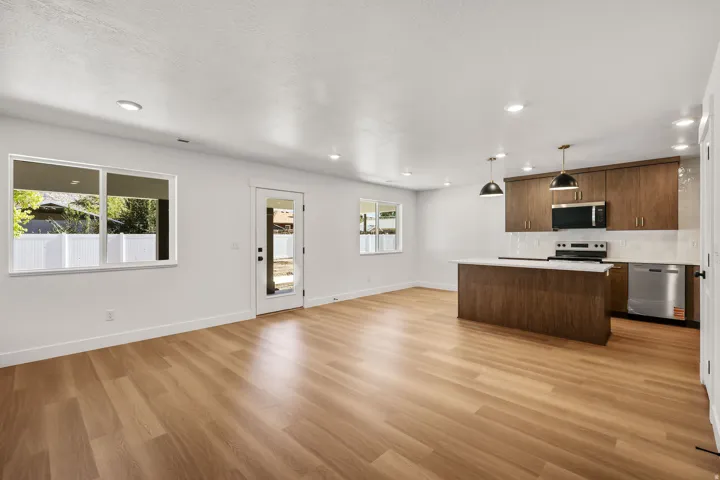 Open-concept living area with wood-finish flooring, white walls, and recessed lighting
