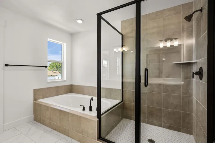 Tiled walk-in shower with a glass enclosure, separate soaking tub with matte black fixtures, and mosaic tile shower floor