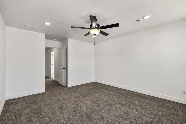 Spacious room featuring neutral carpeting, a ceiling fan with integrated lighting, and recessed lighting