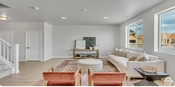 Bright, open-concept living space featuring wood-finish flooring, recessed ceiling lighting, and abundant natural light from large windows. This home is to be built. Pictures are of a similar home.