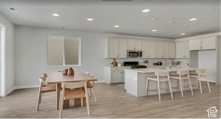 Modern kitchen featuring light-toned cabinetry, stainless steel appliances, a center island with a sink, and recessed lighting. This home is to be built. Pictures are of a similar home.