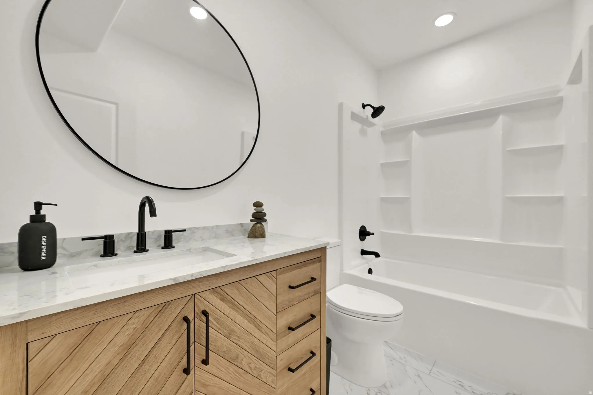 Vanity with wood-finish cabinetry, stone countertop, matte black fixtures, circular mirror, and built-in tub with shower