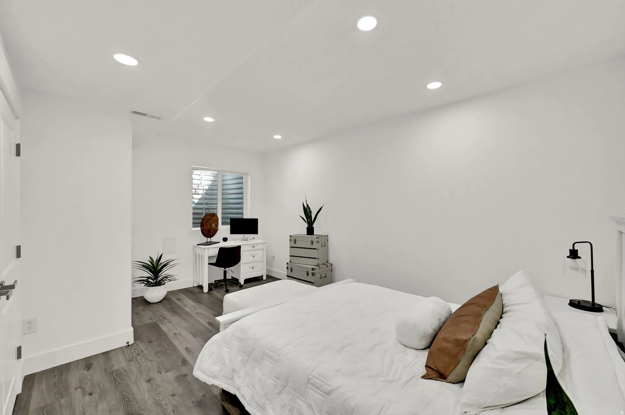 Recessed ceiling lighting, wood-finish flooring, white walls, and a window with horizontal blinds