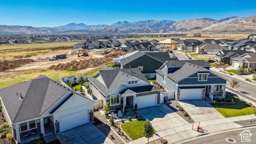 Residential neighborhood with mountain scenery, featuring multiple single-family homes with pitched roofs, attached garages, and manicured landscaping