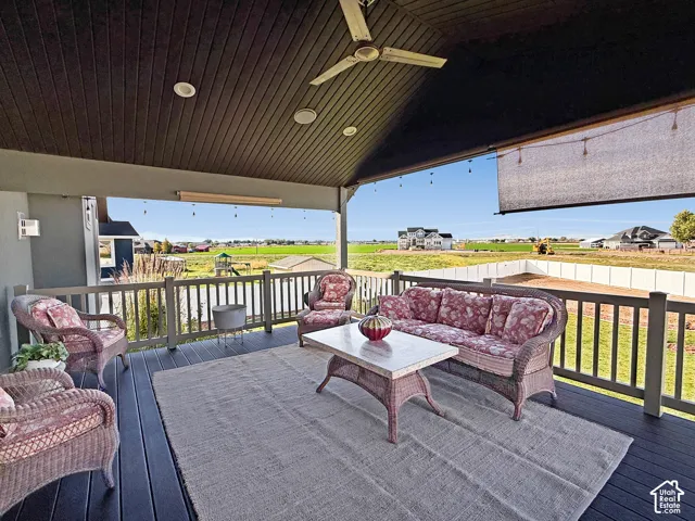Covered outdoor deck with a ceiling fan, recessed lighting, and a roll-down shade