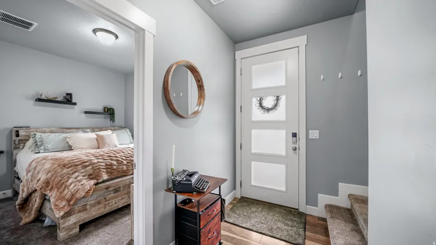 Modern entry door with frosted panels, wood-finish flooring, and a contemporary flush-mount ceiling light