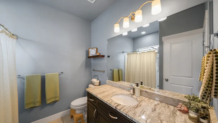 Bathroom featuring a single vanity with a built-in sink, granite countertop, and dark wood-finish cabinetry