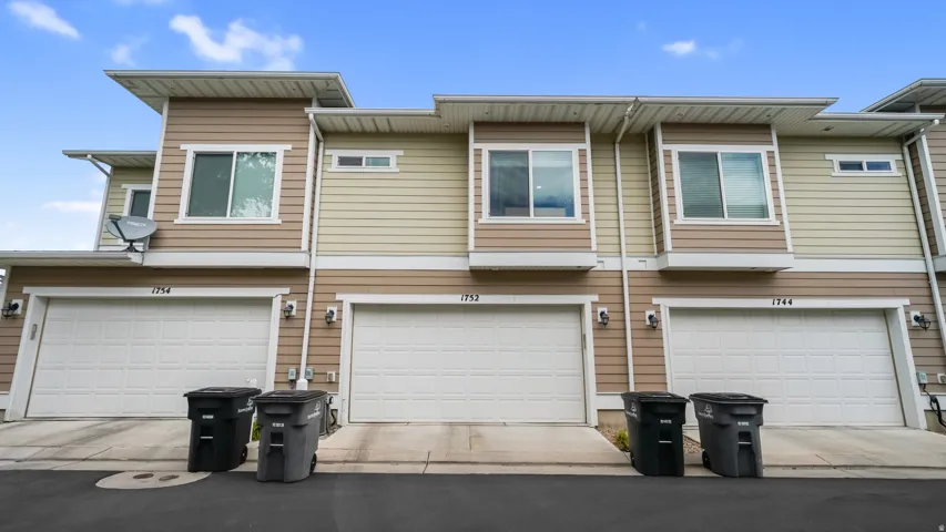 Multi-unit residence featuring neutral-toned siding, white garage doors, and individual driveways
