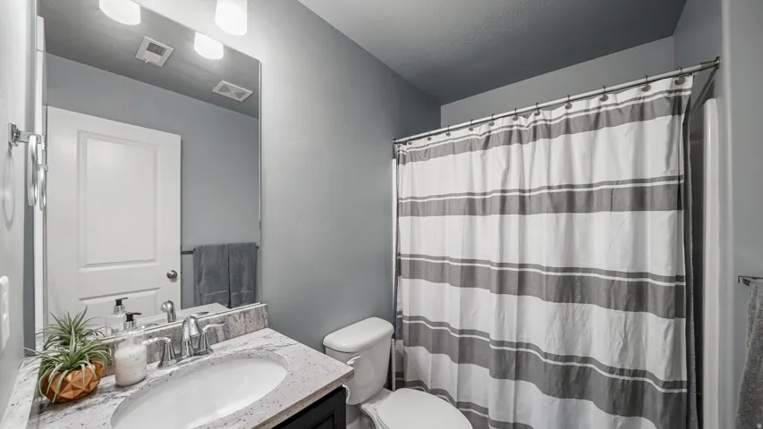 Vanity with a polished chrome faucet, under-mount sink, and speckled countertop
